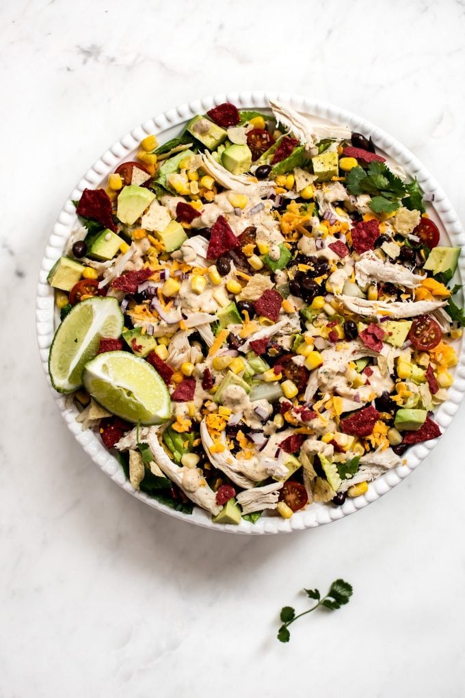 white bowl with healthy chicken taco salad and lime wedges