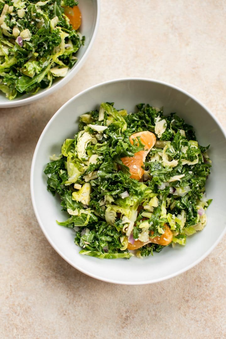two bowls of easy shredded kale and Brussels sprouts salad with pecorino cheese and mandarin oranges