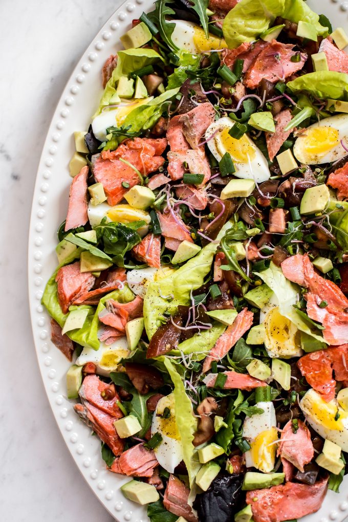 salmon Cobb salad with egg and avocado on a white dish