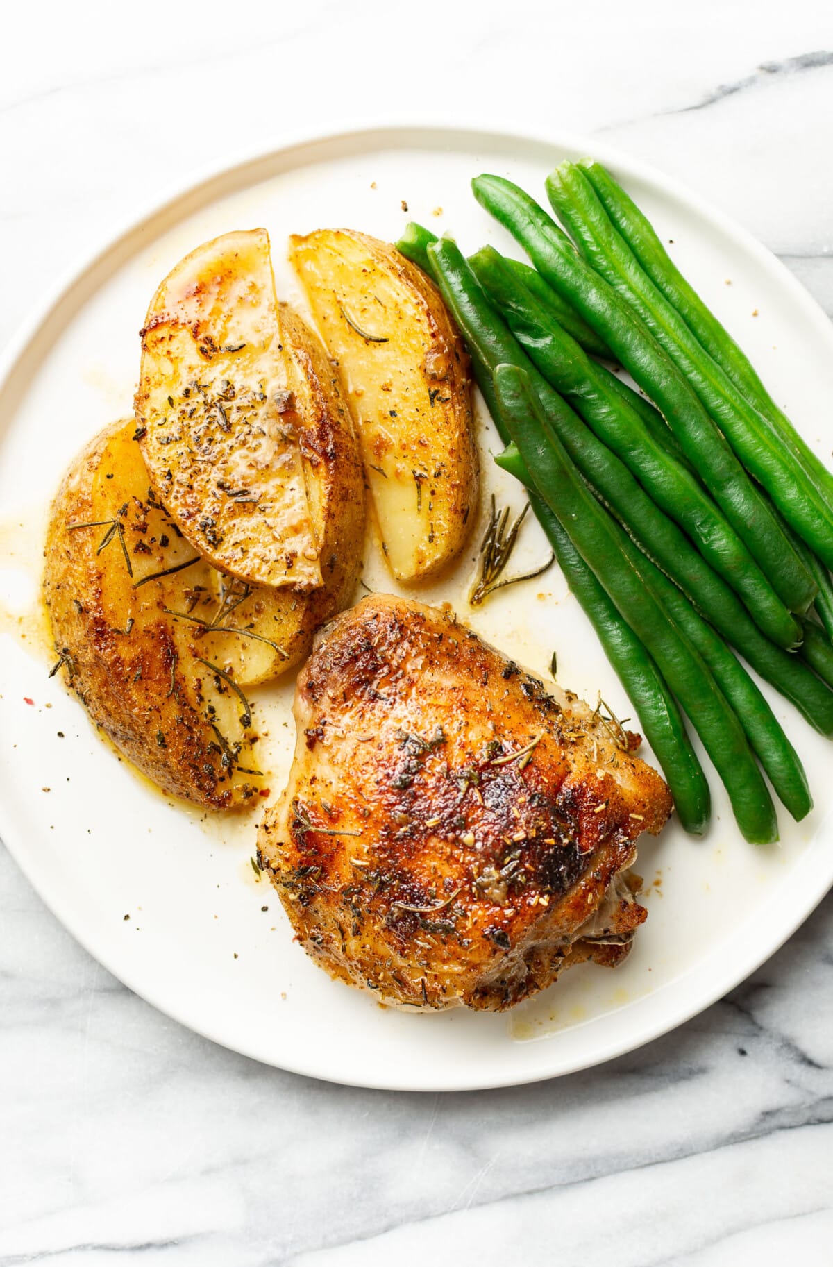 a plate with sheet pan chicken and potatoes along with green beans
