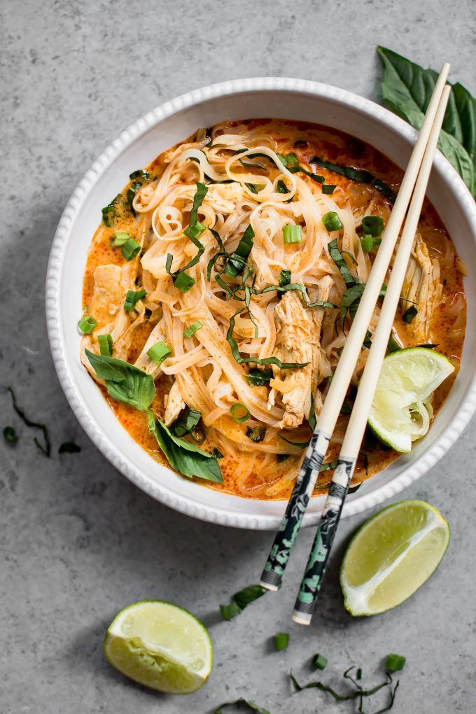 Thai chicken curry soup in a bowl with chopsticks and a lime wedge