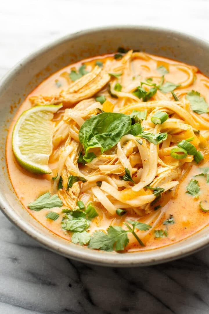 a bowl of thai chicken curry soup garnished with a lime wedge