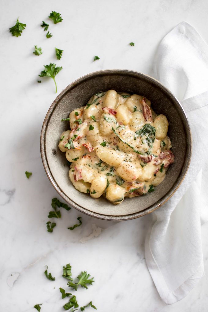 creamy gnocchi with sun-dried tomatoes and basil in a bowl