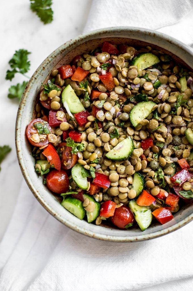 close-up of green lentil salad with tomatoes and cucumber in a bowl