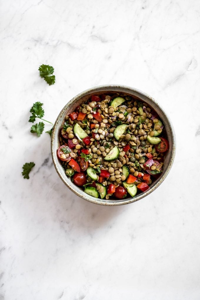 bowl of green lentil salad on a marble surface