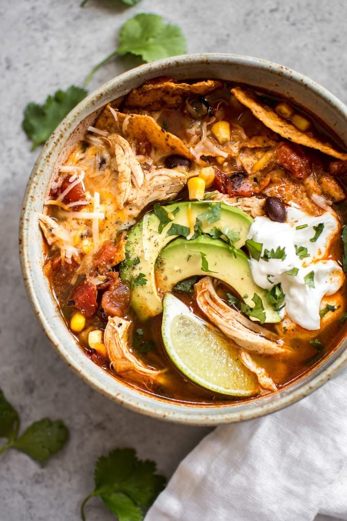 Instant Pot chicken tortilla soup in a bowl and toppings of sour cream, avocado, and lime wedge