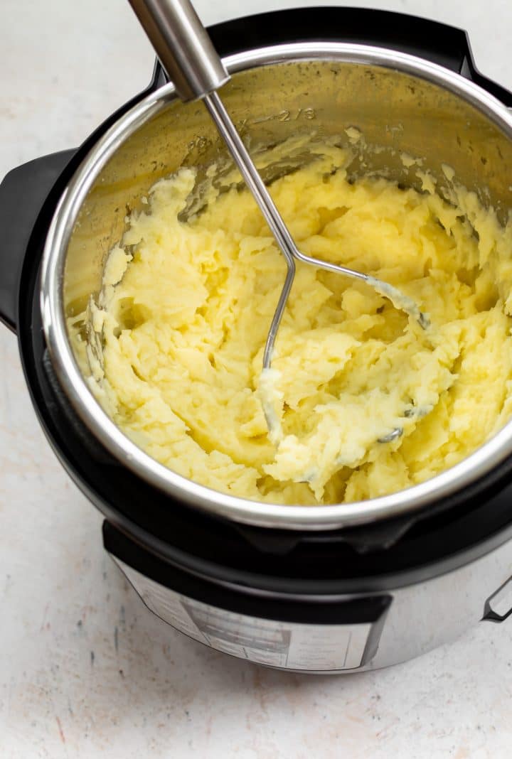 mashed potatoes in an Instant Pot with a potato masher