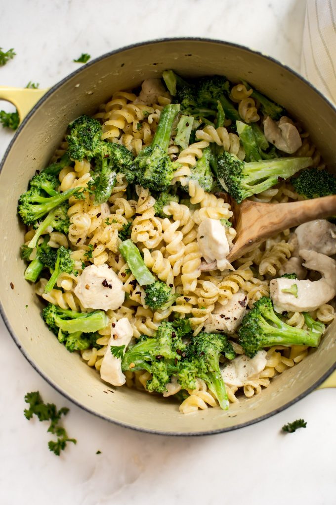 close-up of pot with chicken broccoli pasta and a wooden cooking spoon