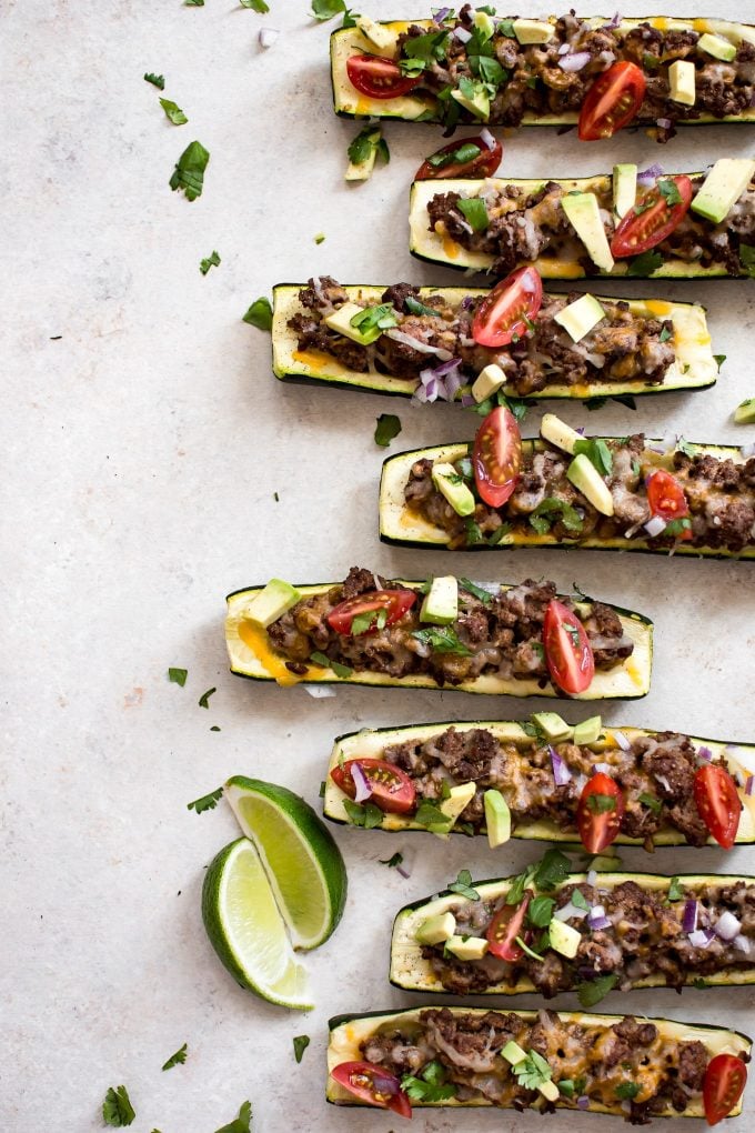 several taco zucchini boats beside lime wedges