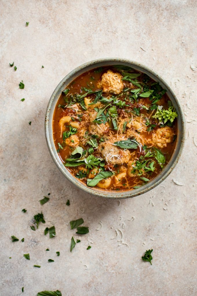 a bowl of turkey meatball soup topped with fresh herbs