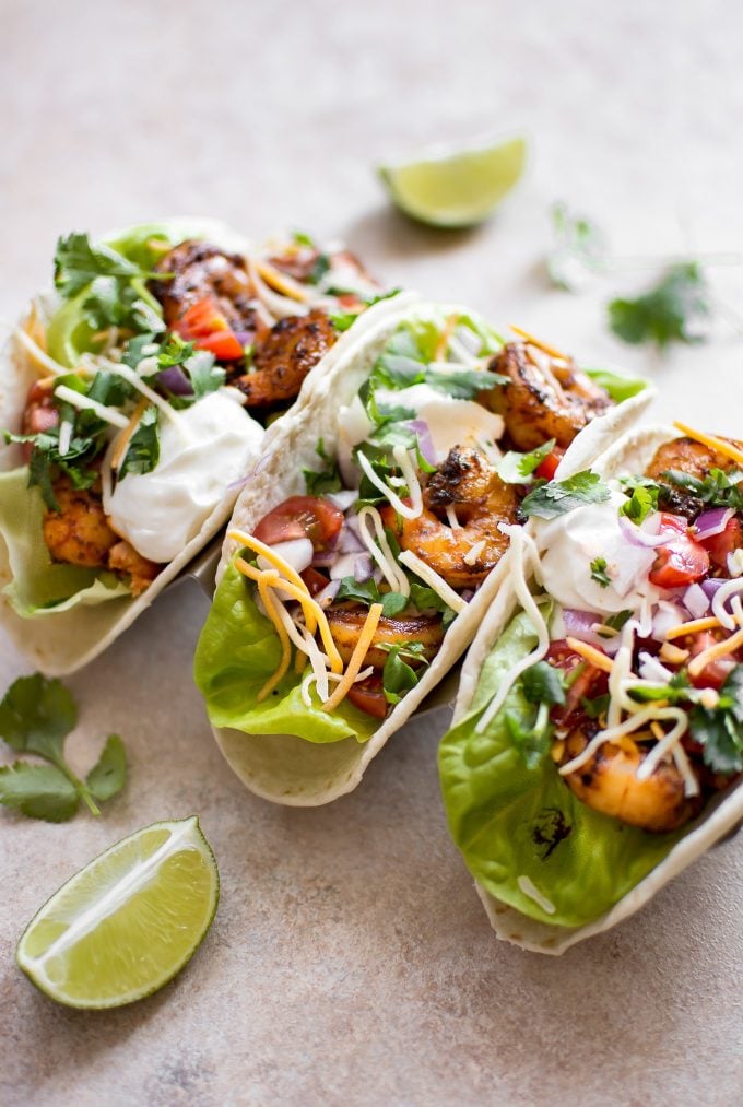 three blackened shrimp tacos with lime wedges