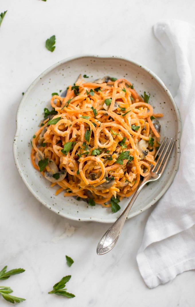 vegetarian creamy mushroom sweet potato noodles on a plate with a fork