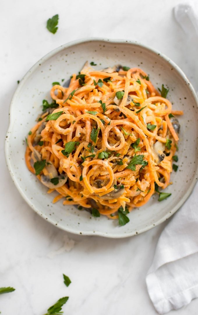 creamy mushroom sweet potato noodles on a plate with parsley garnish