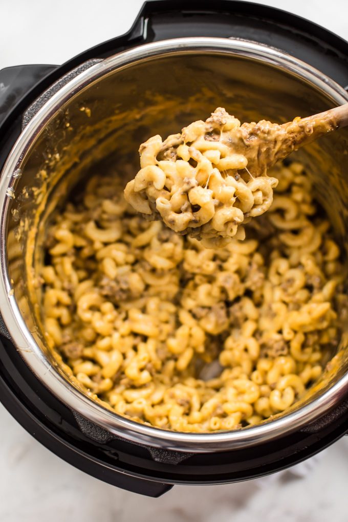 beef macaroni and cheese inside an Instant Pot with a spoonful on a wooden cooking spoon