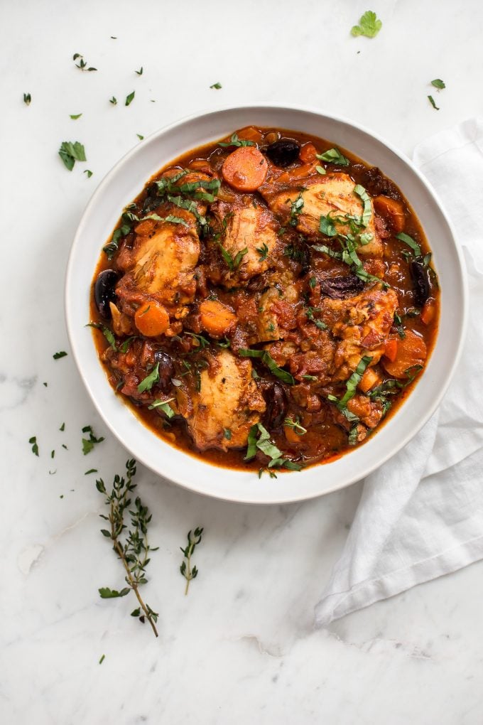 plate of Instant Pot chicken cacciatore with a sprig of herbs and a cloth napkin