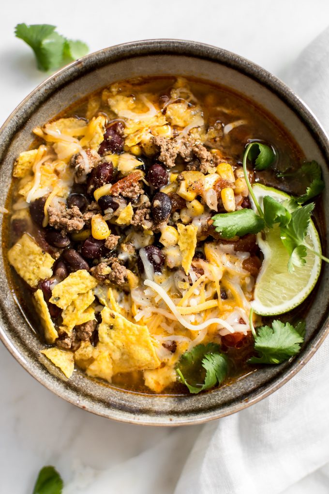 close-up of Instant Pot taco soup with toppings of lime, cilantro, and tortilla chips