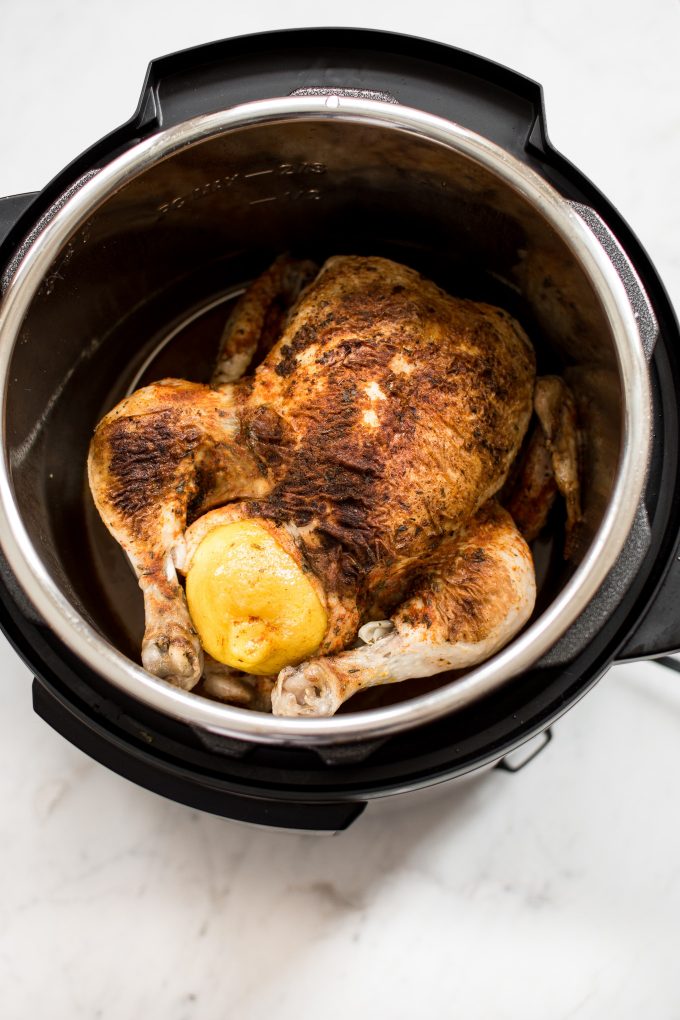 seasoned whole chicken with lemon inside an Instant Pot