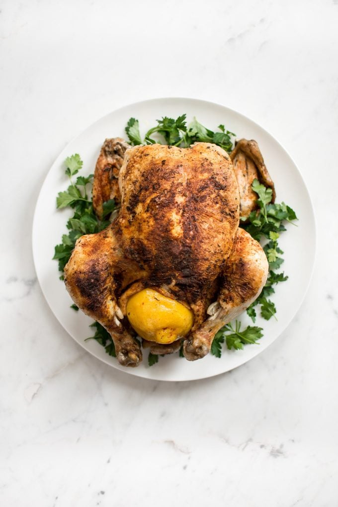 whole chicken from an electric pressure cooker on a white serving plate