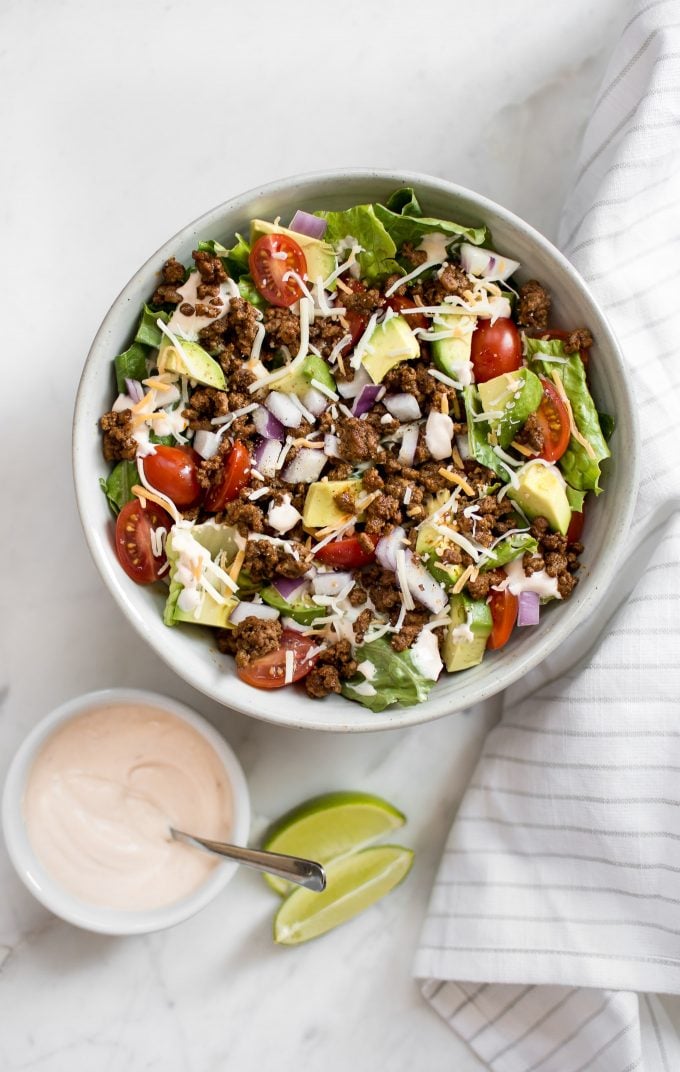 bowl of southwest taco salad beside small dressing bowl with a spoon and lime wedges