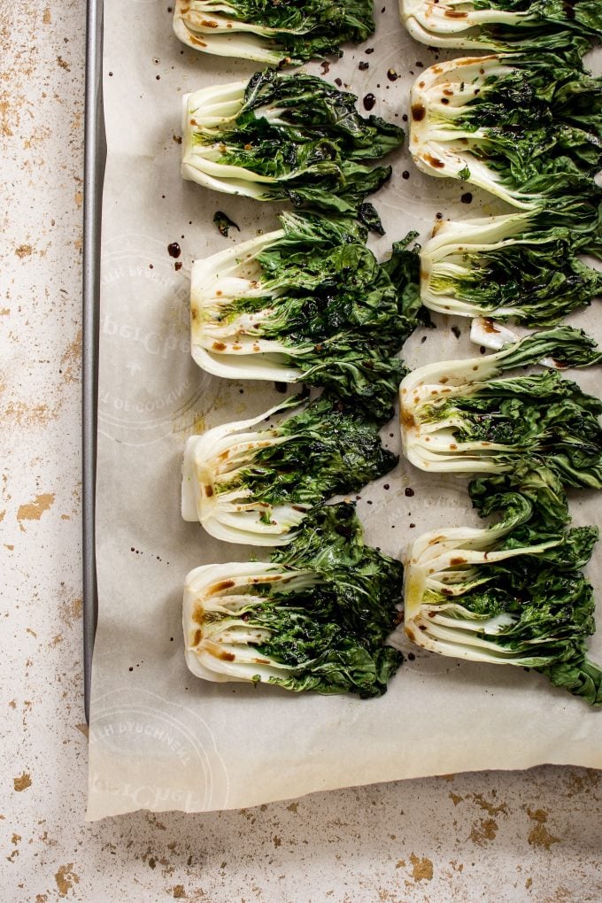 sheet pan with several roasted baby bok choy with garlic, lemon, soy sauce, and chili flakes