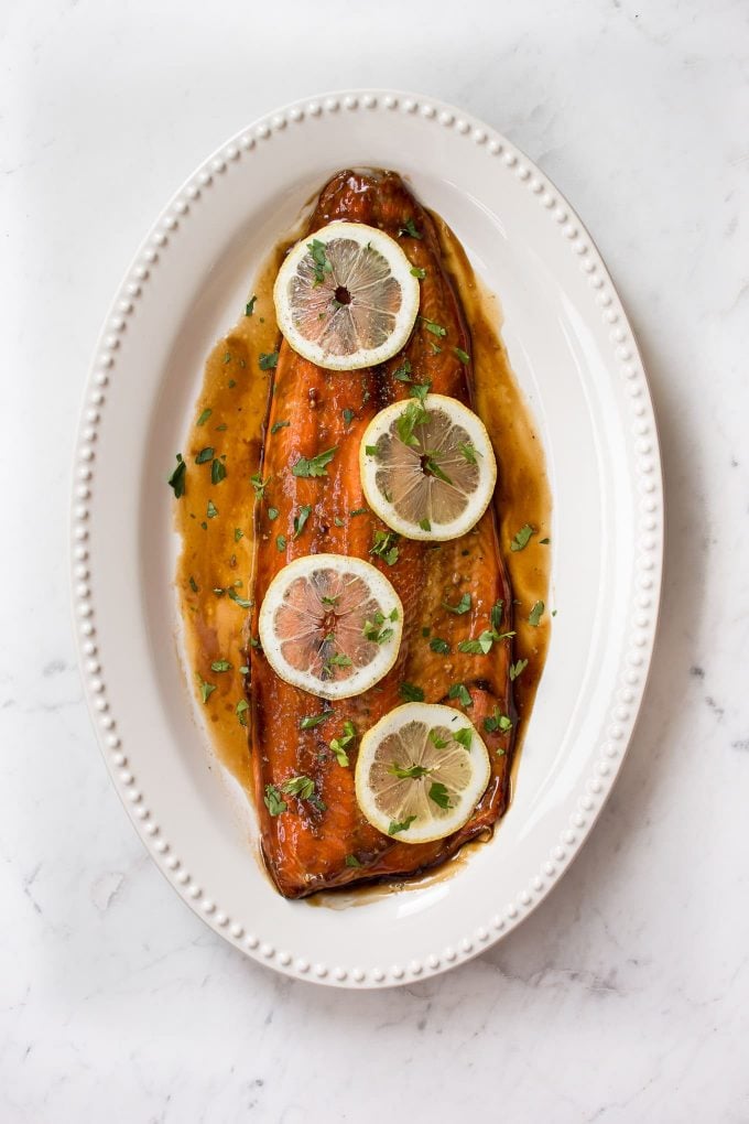 easy baked teriyaki salmon with glaze on an oval white plate with lemon slices