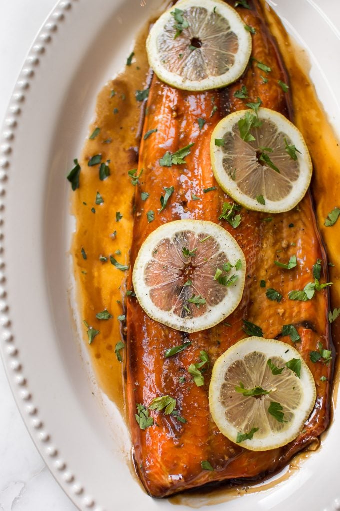 close-up of baked teriyaki salmon on an oval plate with lemon slices