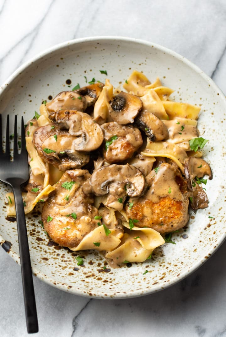 creamy balsamic tenderloin medallions with egg noodles in a shallow bowl