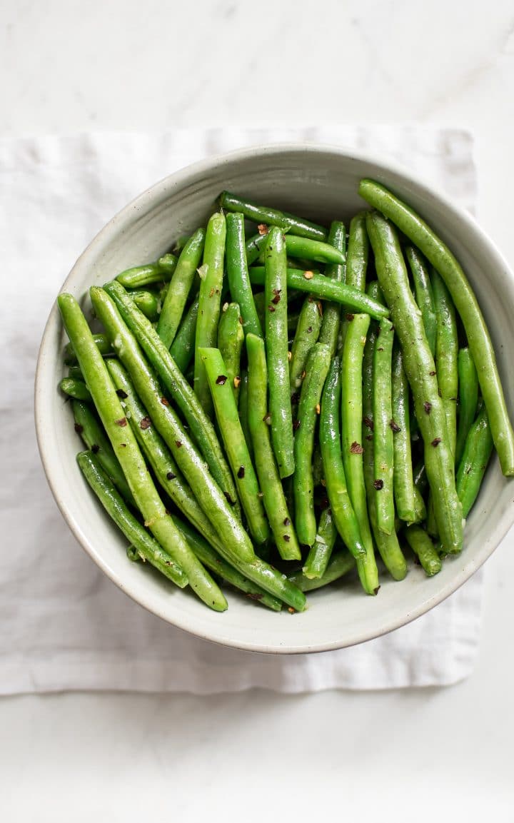 a bowl with fresh green beans seasoned with chili and garlic butter