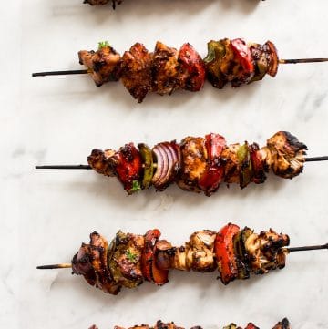 Making chicken kabobs on the grill is fast and easy! A quick marinade, red onions, green and red peppers, and some skewers is all you need to make these healthy chicken kebabs. A delicious summer BBQ recipe!
