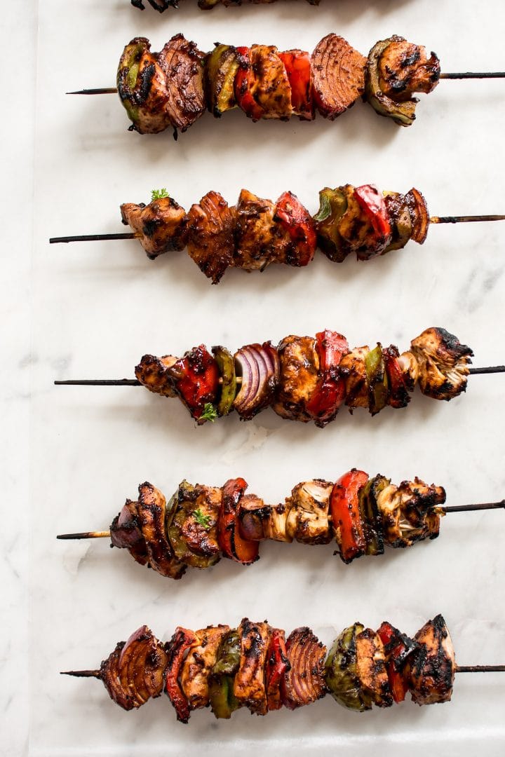 several grilled chicken kabobs with red onions and green and red peppers