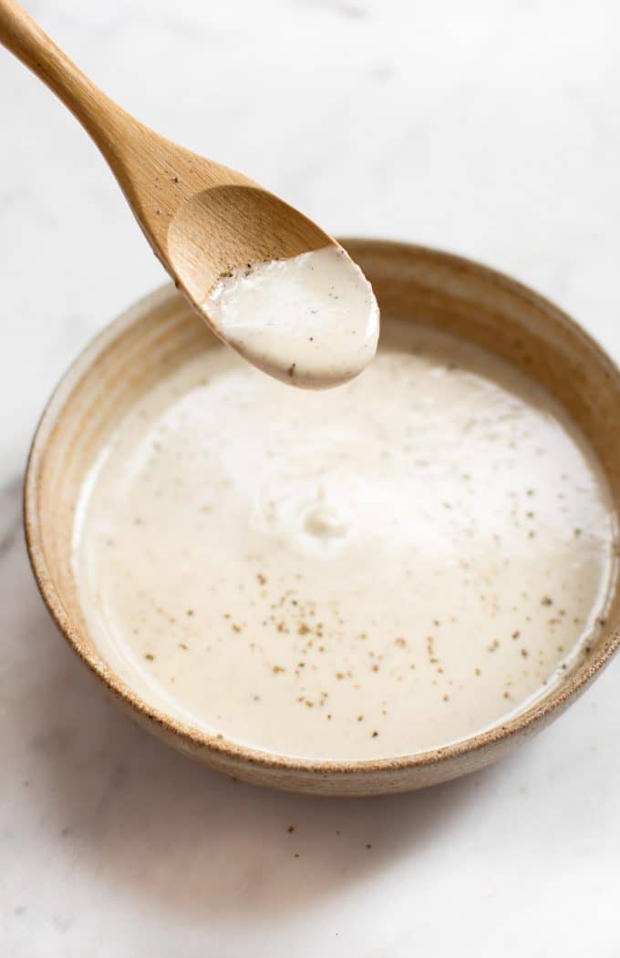 serving bowl with lemon tahini dressing on wooden spoon