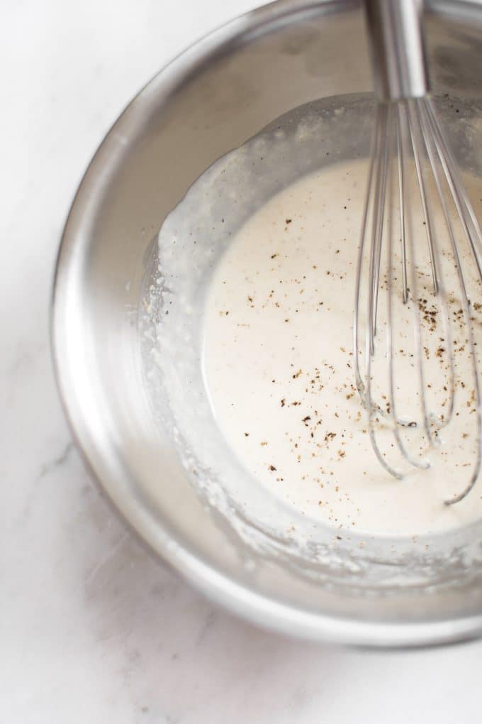 close-up of metal mixing bowl and whisk with easy vegan lemon tahini dressing