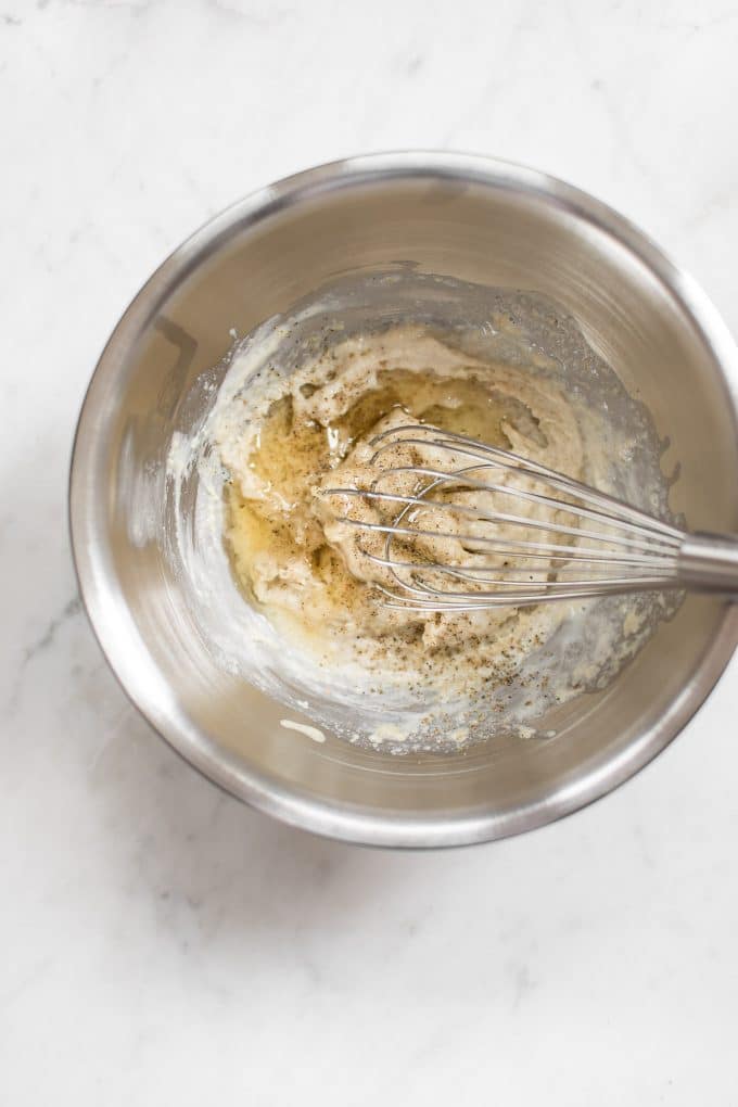 metal mixing bowl with easy lemon tahini dressing ingredients and a metal whisk