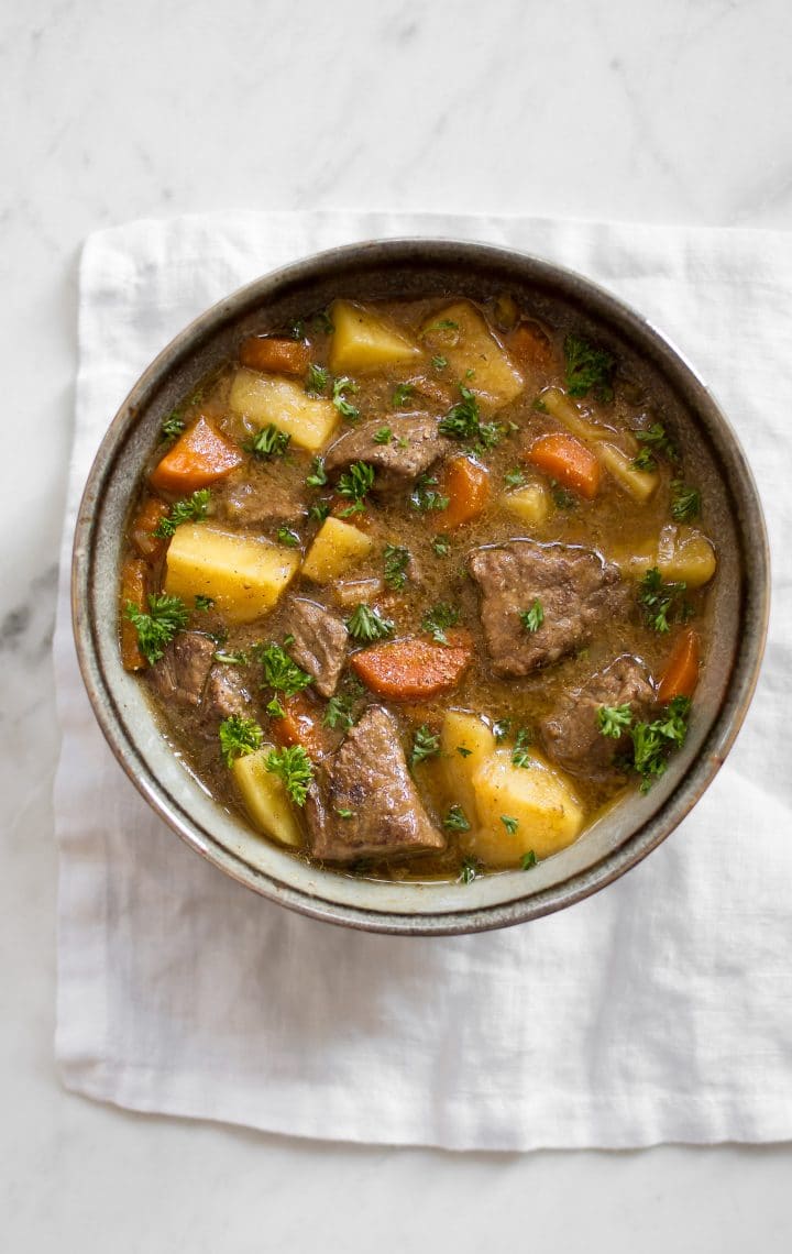 bowl with Instant Pot Irish beef stew with tender beef pieces, potatoes, carrots, and a Guinness broth