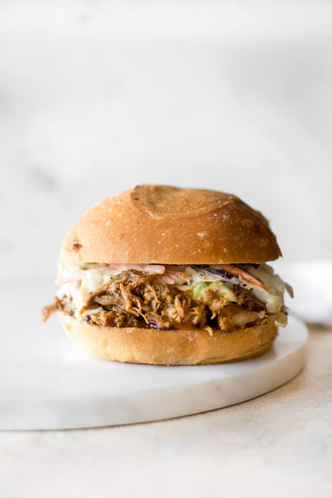 sandwich with easy Instant Pot pulled pork, homemade coleslaw, and a bun on a marble surface