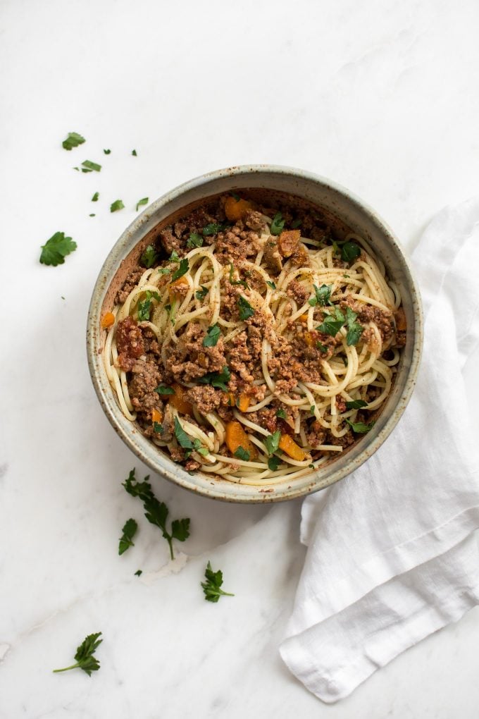 bowl of spaghetti with electric pressure cooker pasta sauce with parsley garnish and a cloth napkin