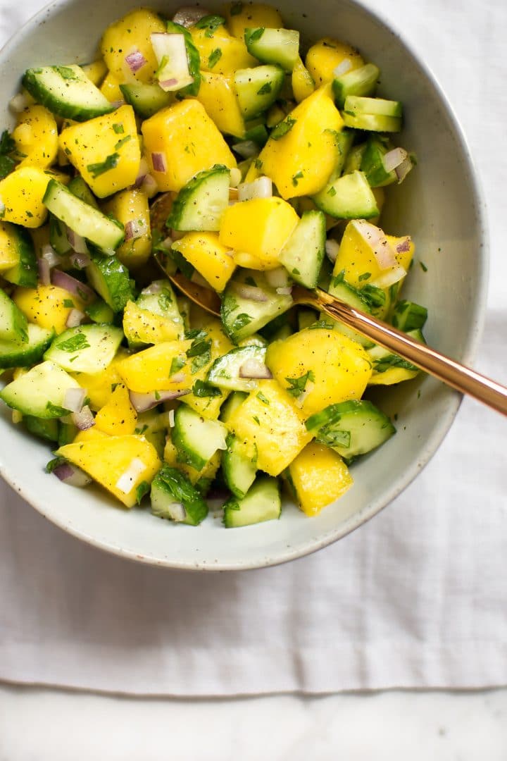 close-up of mango salsa in a white bowl with a spoon