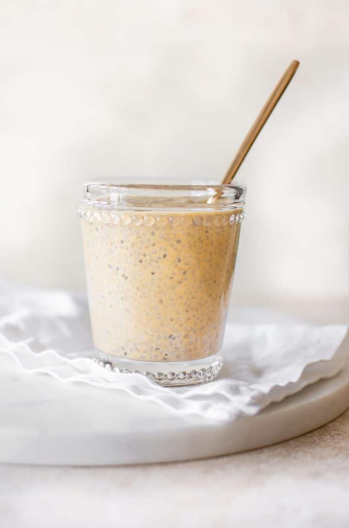 clear glass jar with pumpkin chia pudding and a spoon