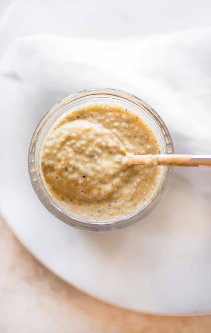 close-up of vegan pumpkin chia pudding on a spoon in a glass jar