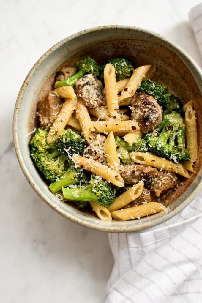 close-up of broccoli sausage pasta with grated parmesan in a bowl