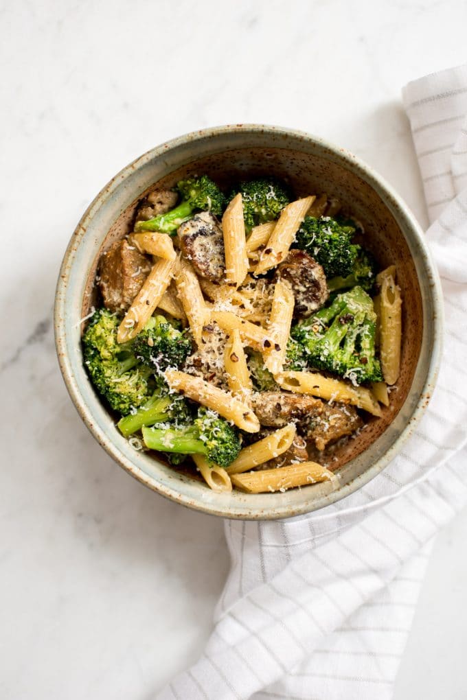 a bowl of sausage and broccoli penne and grated parmesan