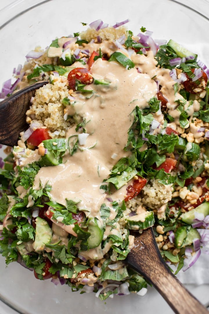 close-up of peanut lime dressing on Thai quinoa salad with wooden salad utensils