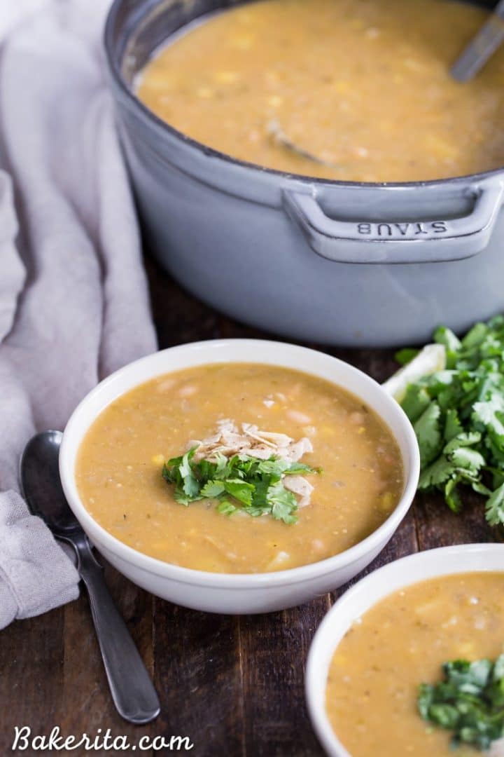 a pot of vegan white bean chili beside two bowls of white bean chili and a spoon