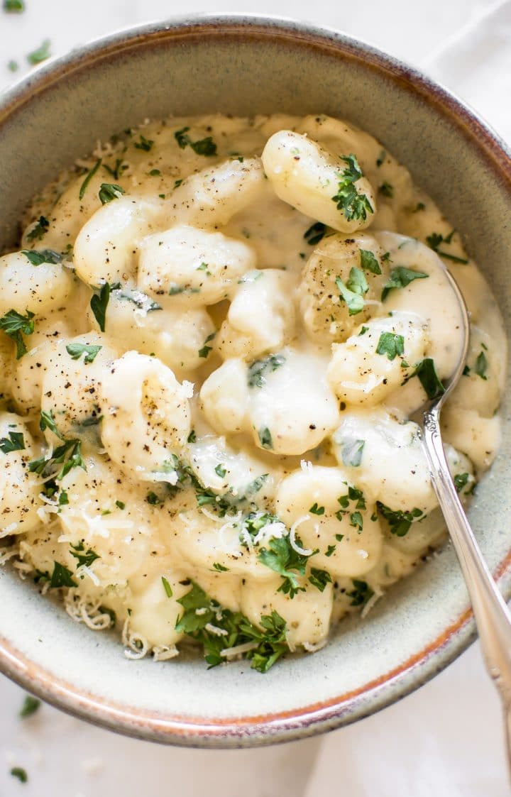 close-up of creamy alfredo gnocchi with a spoon in a bowl