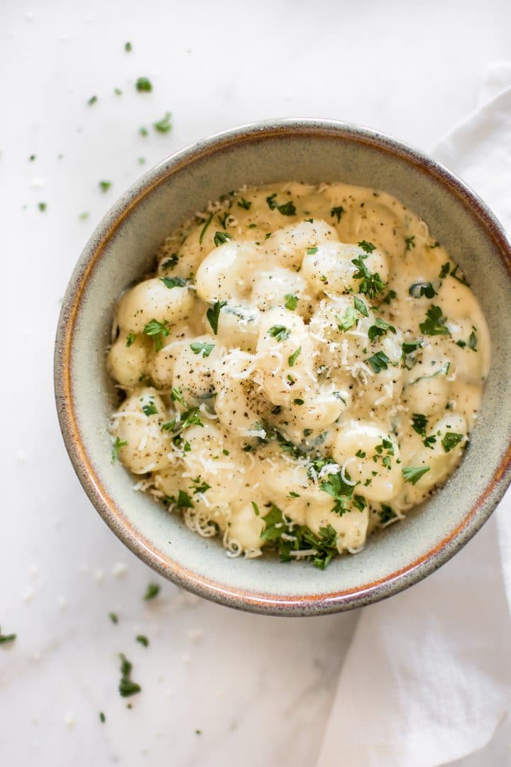 bowl of creamy alfredo gnocchi with grated parmesan on top