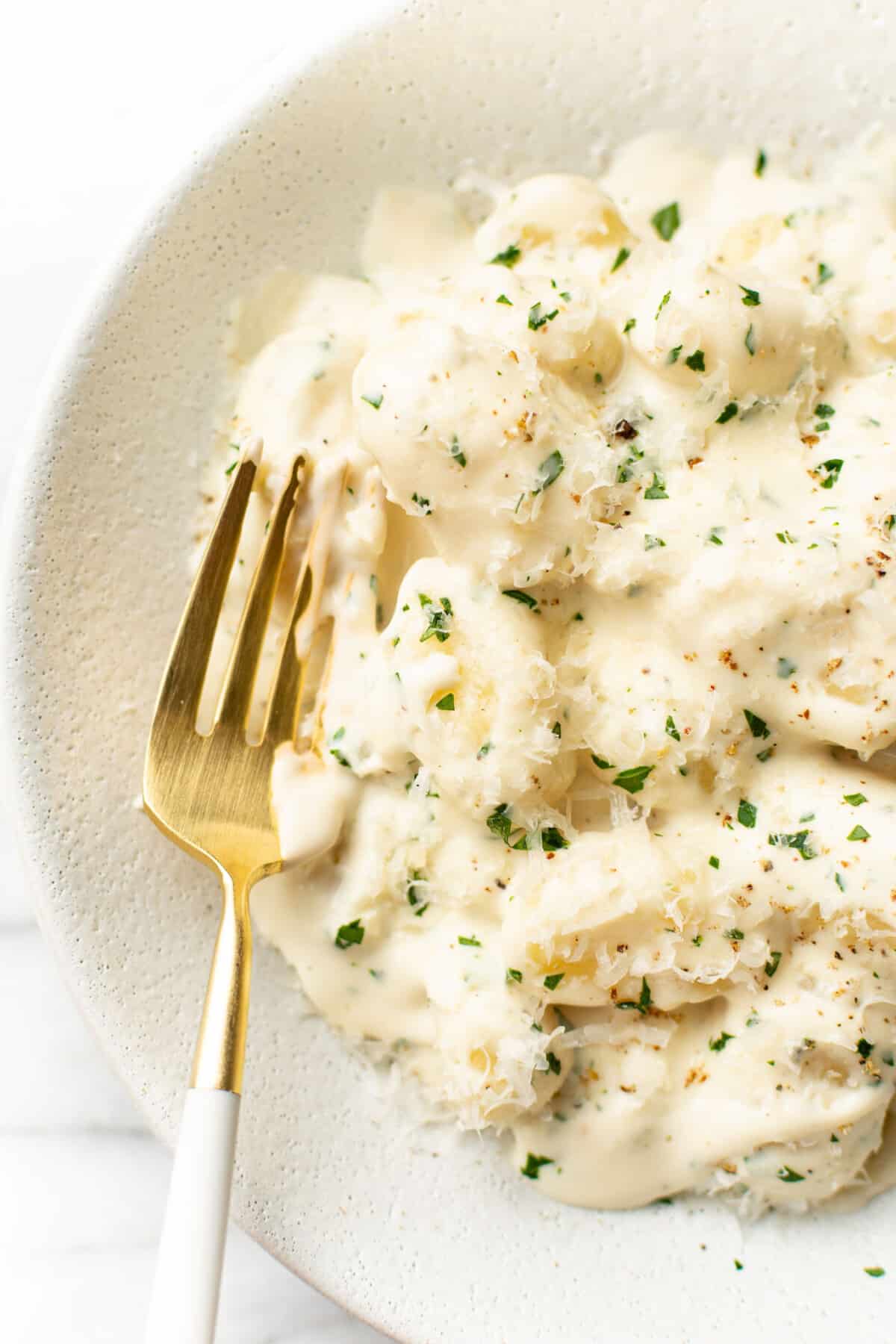 a bowl of alfredo gnocchi with a fork