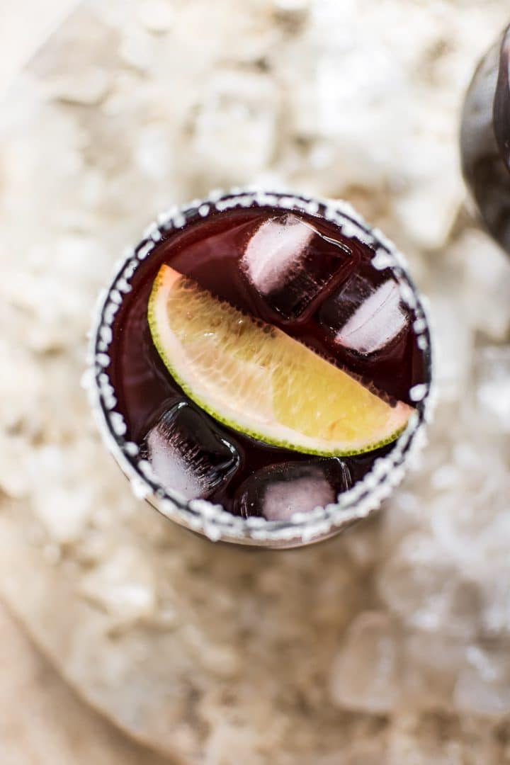 close-up of easy black cherry margarita on the rocks with lime wedge in a glass