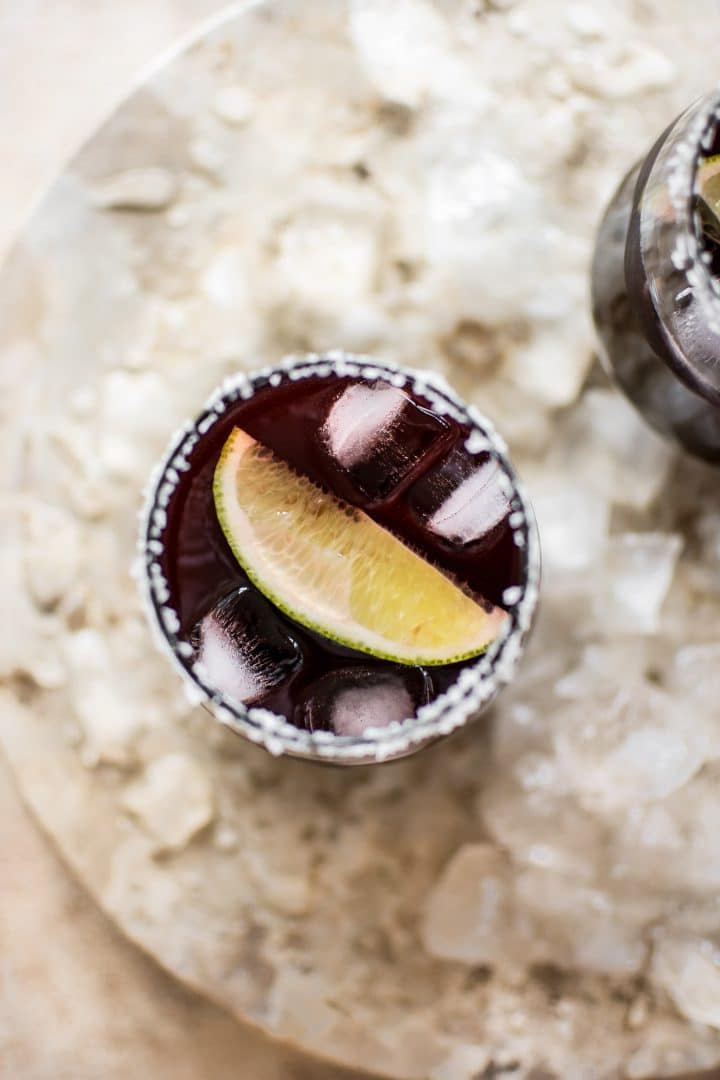 black cherry margarita in salt rimmed glass with a lime wedge