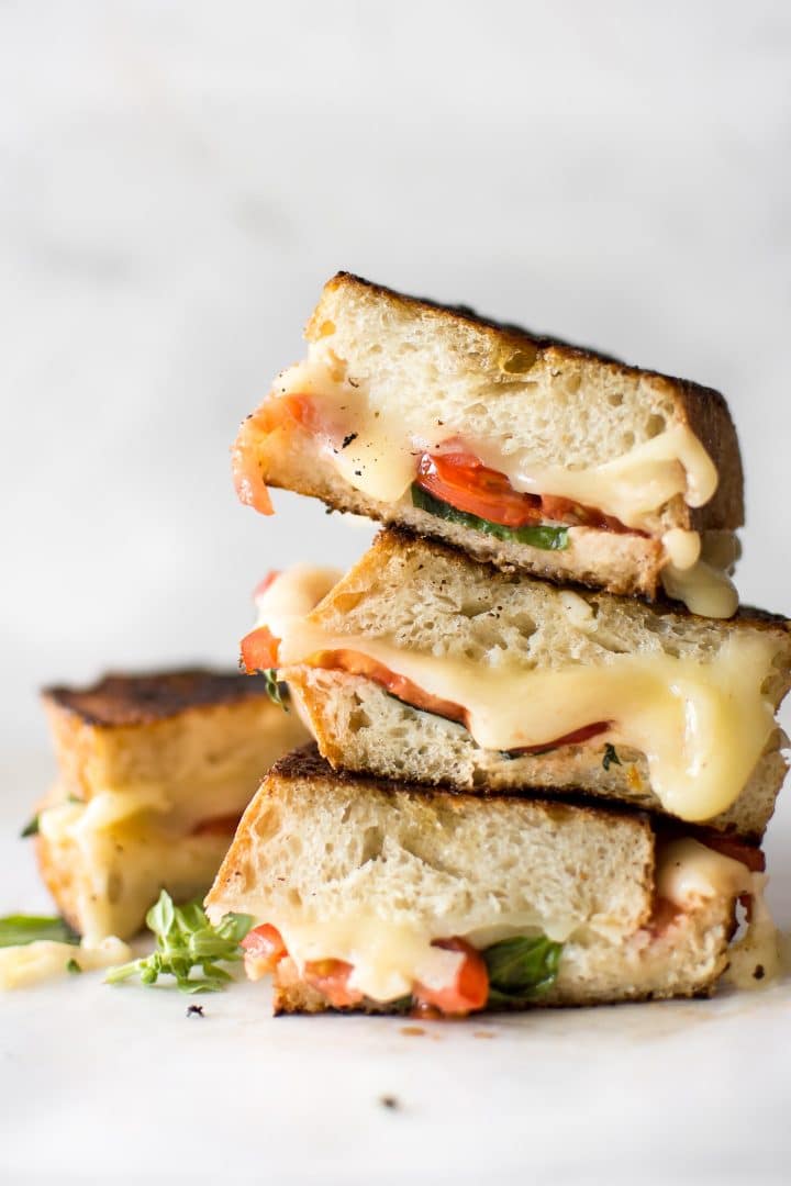 a stack of Caprese grilled cheese sandwiches with melting cheese