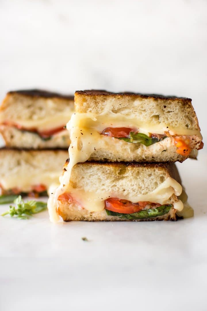 a close-up of stacked Caprese grilled sandwiches with tomatoes, basil, and mozzarella